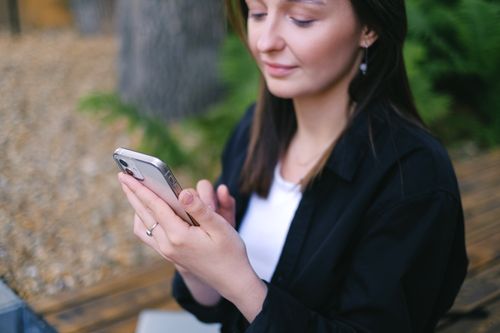 Free Woman using smartphone outdoors, embracing leisure and relaxation. Stock Photo