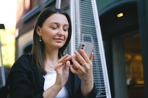 Free Young woman using a smartphone outside, smiling and connected. Stock Photo