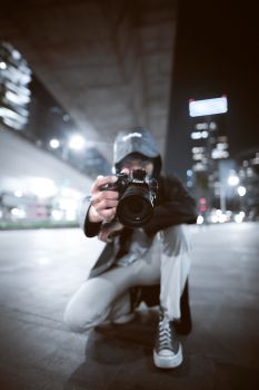 Crouching photographer captures the city nightlife in Jakarta, highlighting urban creativity.