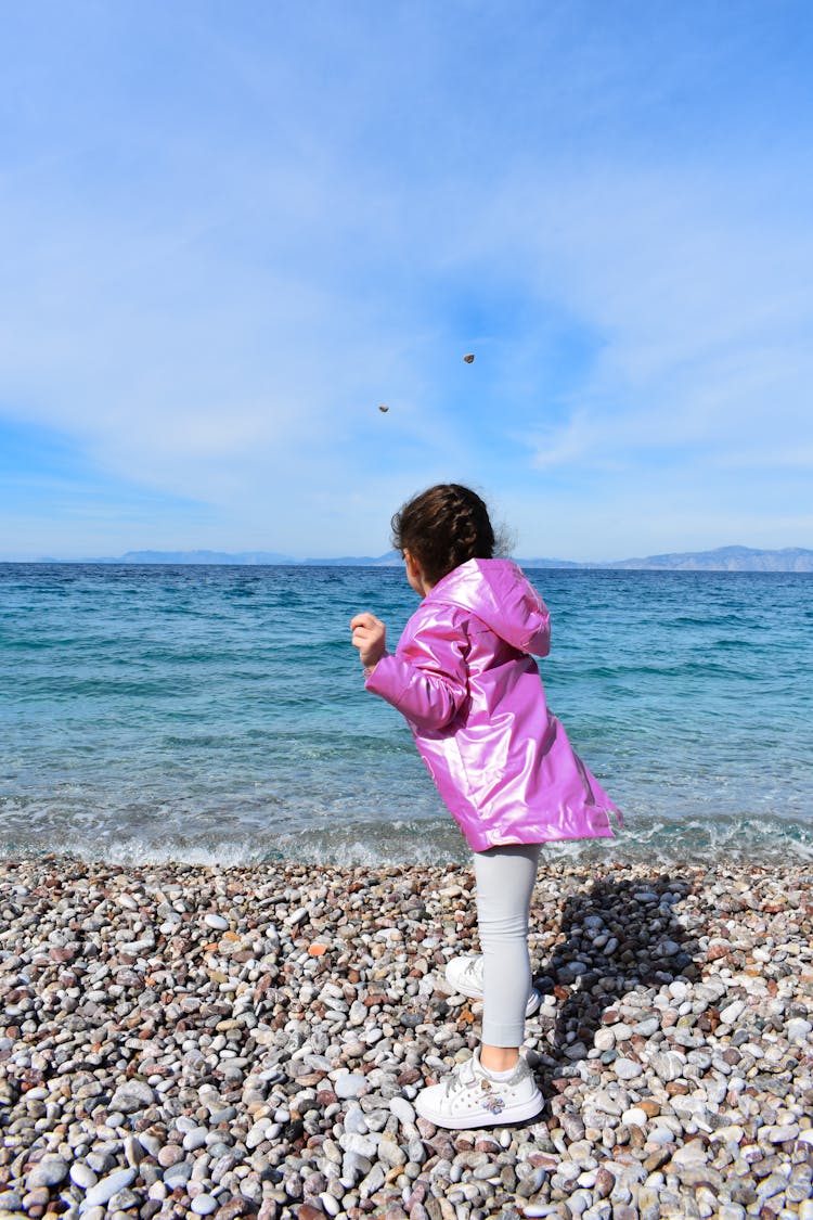 The Girl Is In A Position Of Throwing A Rock In The Sea