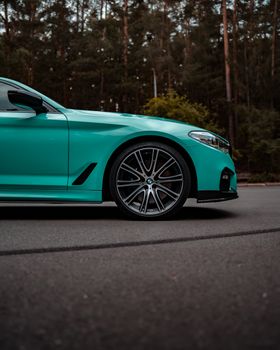 Sleek green sedan parked on a forest road, showcasing modern automotive design.