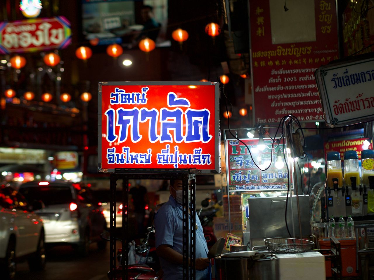 a bustling urban street at night with illuminated signs and vibrant ma