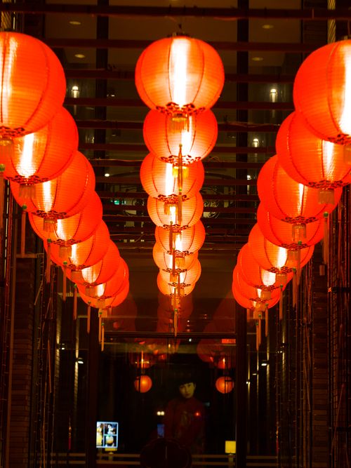 Free A hallway adorned with vibrant red Chinese lanterns hanging in an elegant indoor setting. Stock Photo