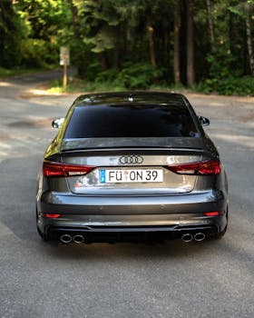A sleek Audi car parked on a forest road, emphasizing the vehicle's design and elegance.