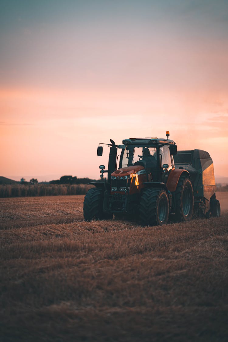 Photo Of A Tractor On The Field At Sunset