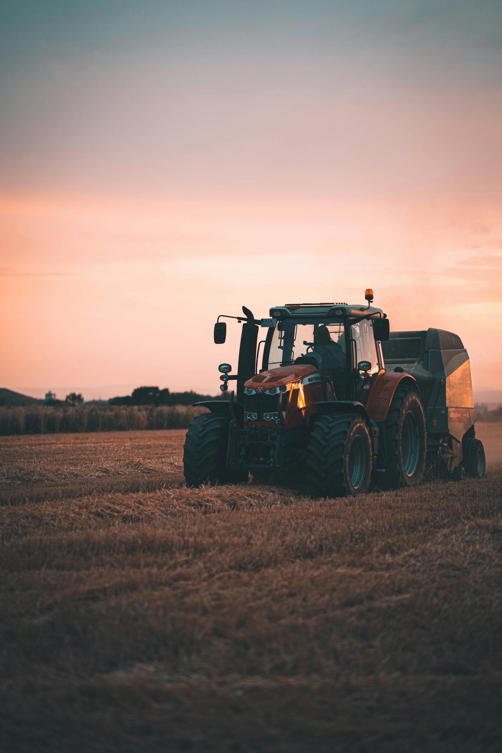 Case tractor pulling a baler in a field