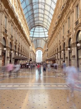 Blurred motion photo capturing people in historic Galleria Vittorio Emanuele II, Milan.