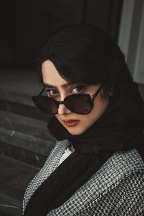Free Elegant woman with dark sunglasses and scarf, displaying a confident expression. Stock Photo