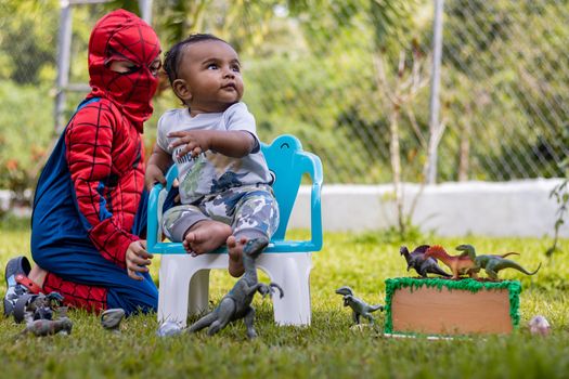 Kids enjoying playtime with dinosaur toys and costumes in a sunny garden.