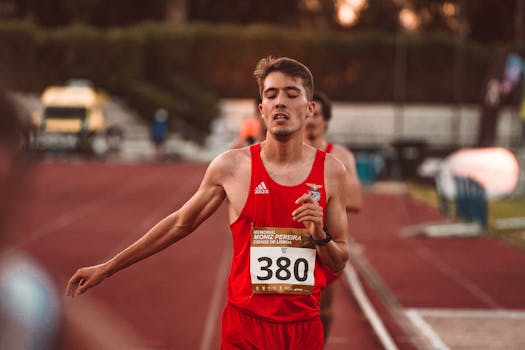 A young male runner crossing the finish line on a track, demonstrating determination and effort.