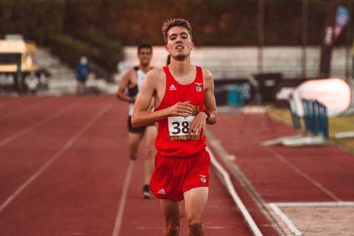 Free Exhausted male runner in red sports attire on track during daytime race, showcasing endurance and fitness. Stock Photo