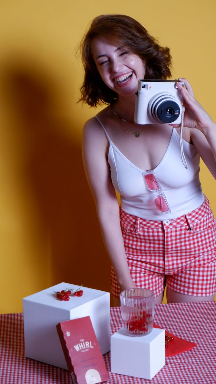 Woman Holding A Polaroid Camera While Laughing