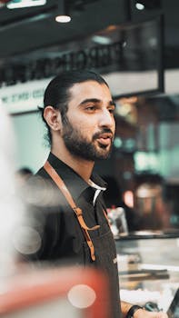 Barista wearing apron, working in a café environment.