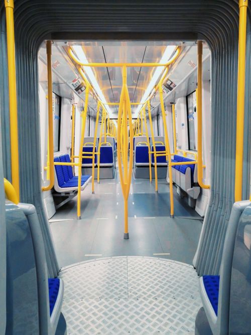 Free Empty tram interior showcasing vibrant yellow railings and blue seats. Stock Photo
