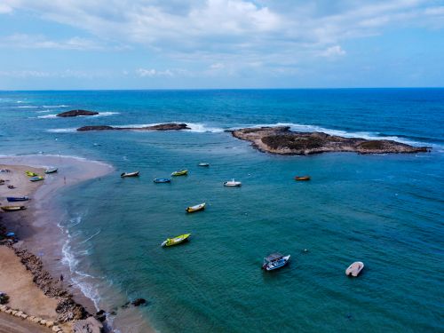Free Aerial view of colorful boats anchored near a peaceful island coastline under blue sky. Stock Photo