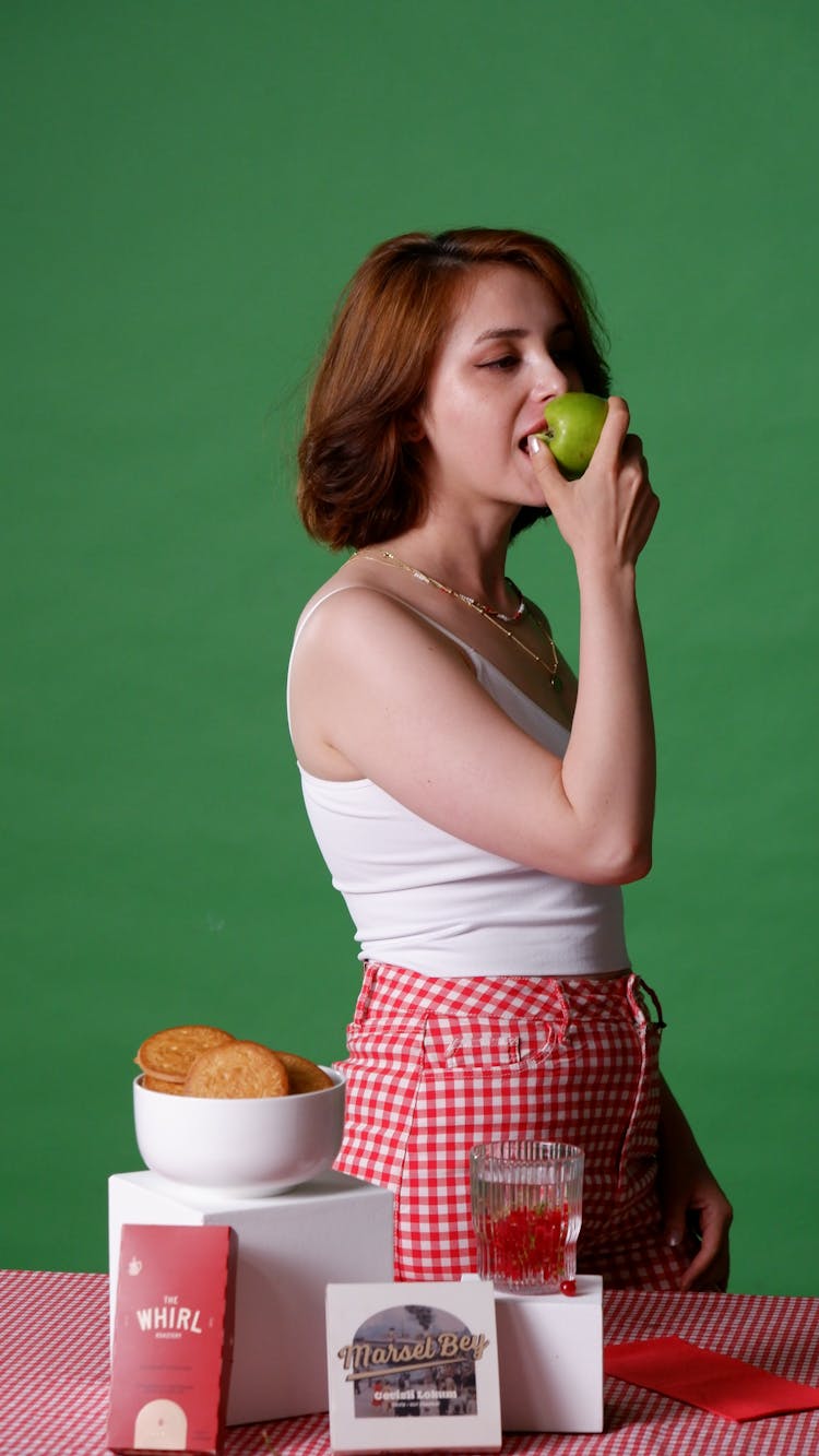 A Woman Biting A Green Apple