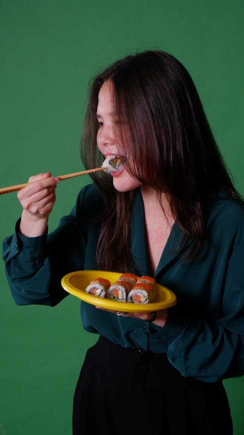 Close-Up Shot of a Woman Using Chopsticks while Eating Sushi Rolls