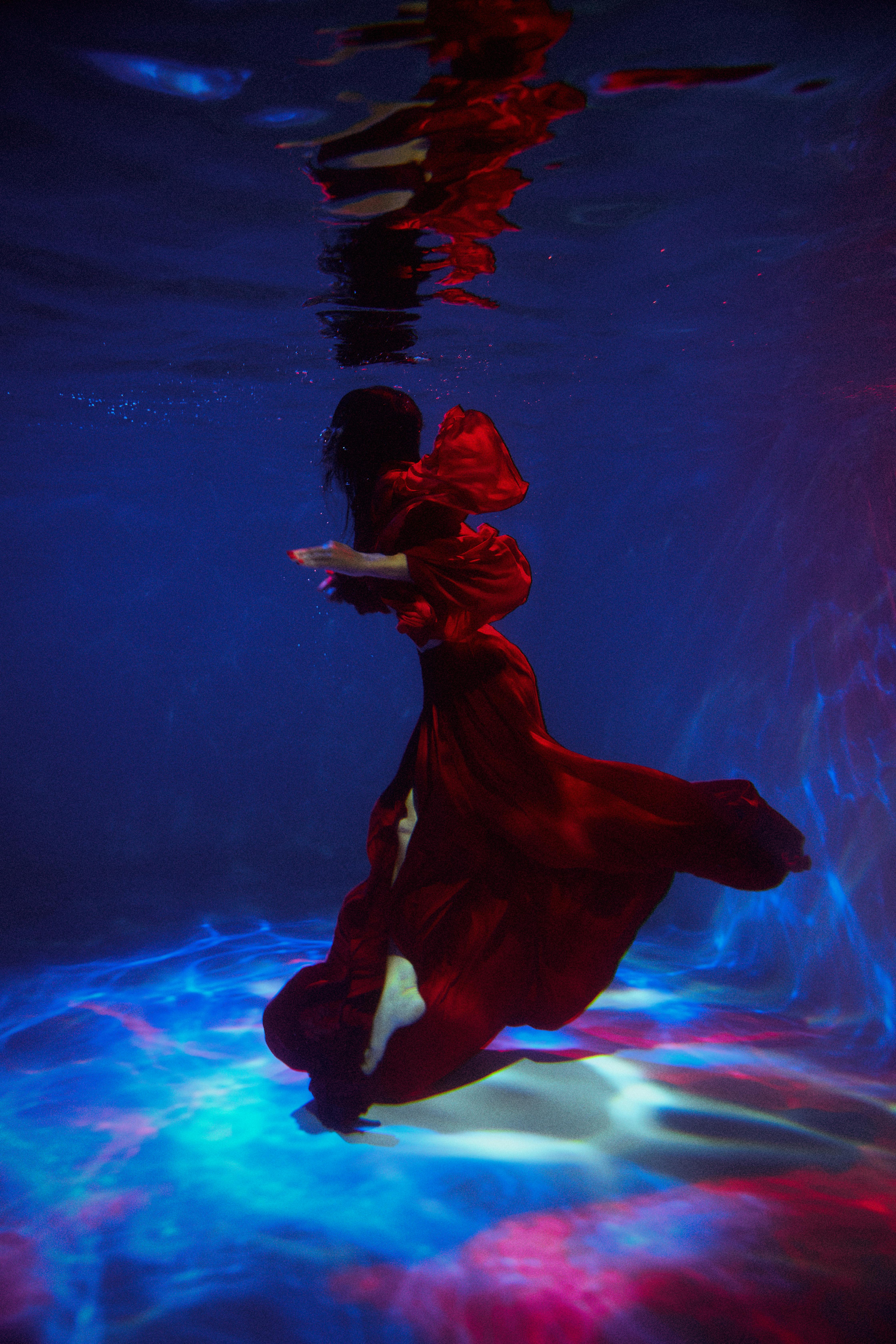 woman fashion model in red dress posing underwater