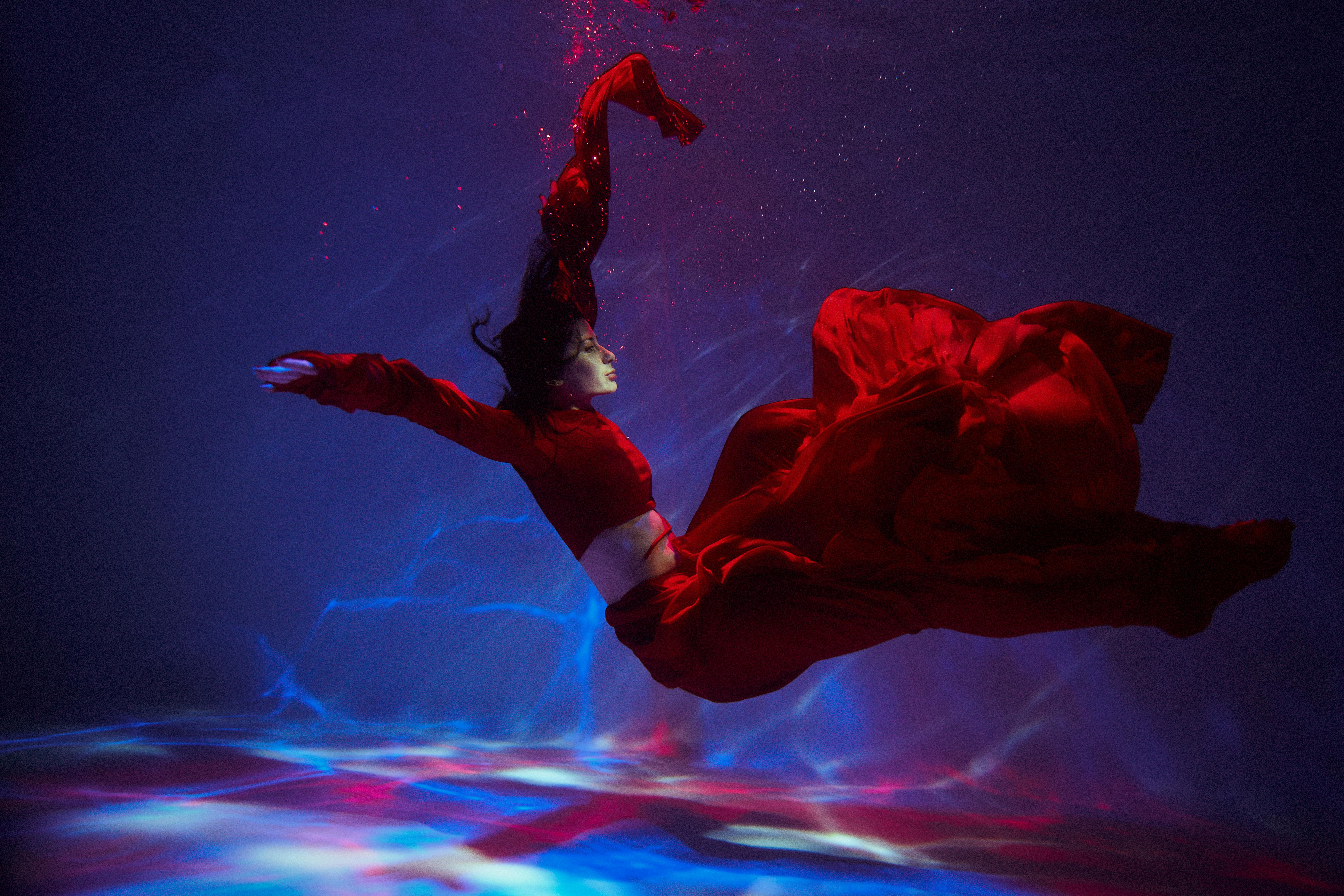 woman in long red dress floating underwater