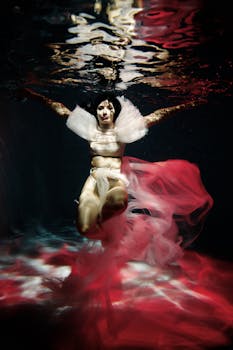 A stunning underwater photo featuring a woman with flowing fabric and vibrant lights, creating a dreamlike effect.