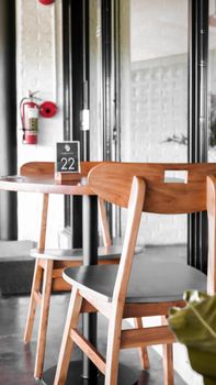 A stylish café interior featuring wooden chairs, a table with an order number, and large windows.