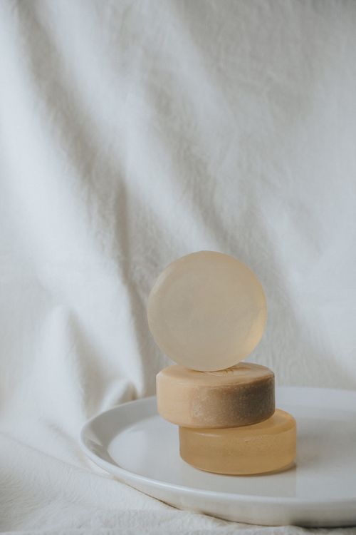 Free Elegant vertical arrangement of round soap bars on a white plate against a neutral background. Stock Photo