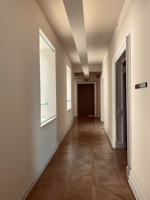 Free Elegant corridor with natural lighting and wooden floor creating a minimalist interior aesthetic. Stock Photo