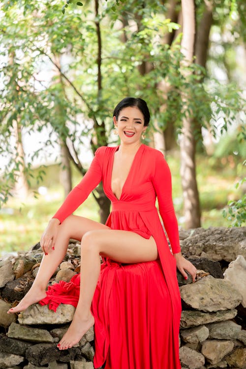 A Beautiful Woman in Red Dress Sitting on the Rocks