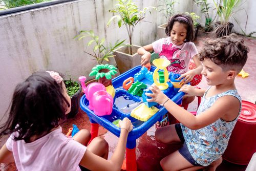 Free Three kids enjoy playing with colorful water toys on an outdoor balcony. Stock Photo