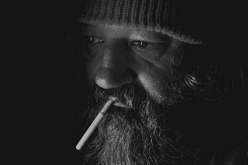 A Close-up Shot of an Elderly Man Smoking Cigarette
