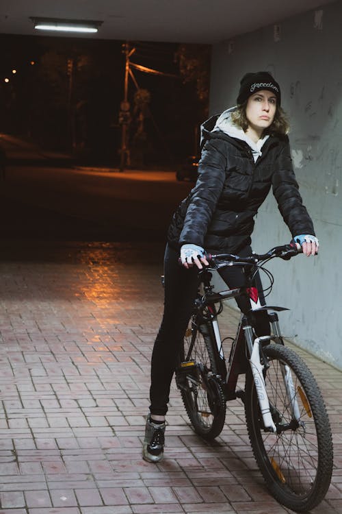 그녀의 자전거를 타고 검은 코트를 입고 여자