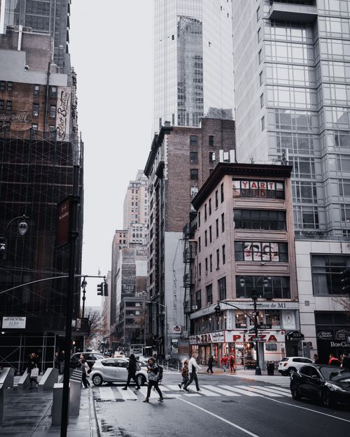 Free Urban street scene in New York City with people, cars, and towering skyscrapers in the background. Stock Photo