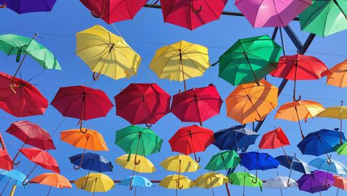 Free A lively display of multicolored umbrellas hanging under a clear blue sky. Stock Photo