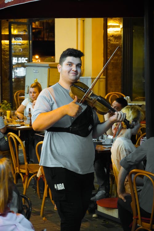 A Man in Gray Shirt Smiling while Playing Violin