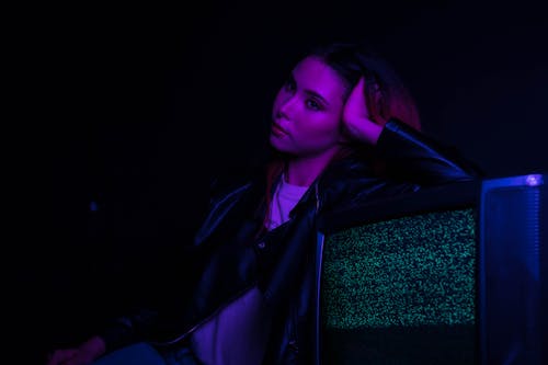 Woman in Black Leather Jacket Leaning on Chair