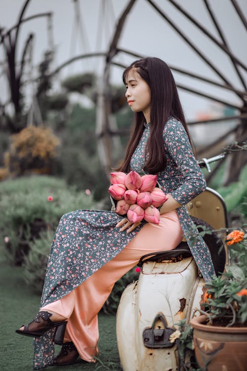 女人坐在摩托車上，按住香蕉花花束