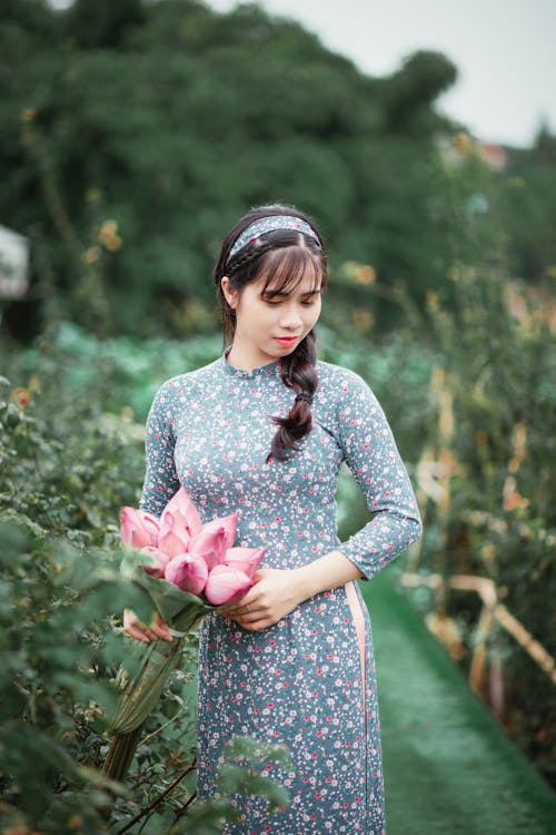 Vrouw Met Roze Bloemen Terwijl Naar Beneden Kijkt