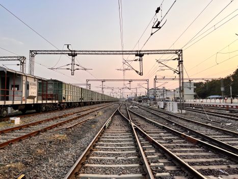 Captivating sunset over railway tracks at Kazipet Junction, India, with a freight train passing by.