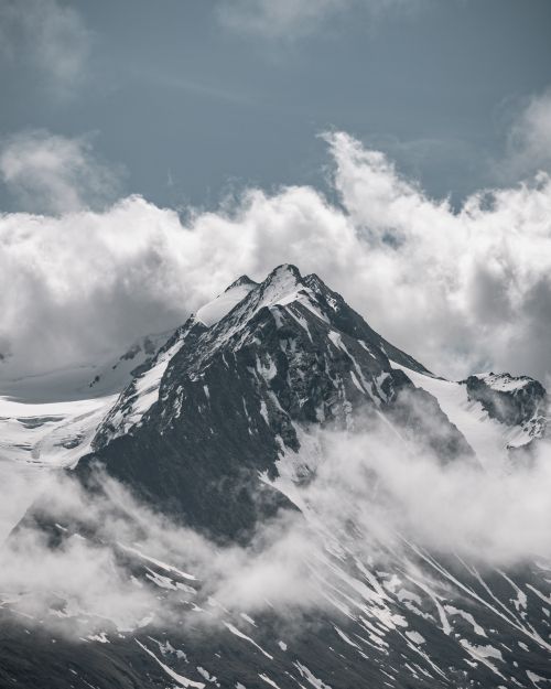 Free A breathtaking snow-capped mountain peak surrounded by clouds, showcasing the beauty of nature. Stock Photo