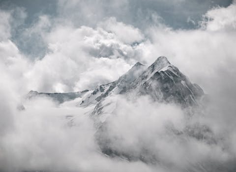 Breathtaking view of snow-covered Tyrolean mountains shrouded in mist and clouds.