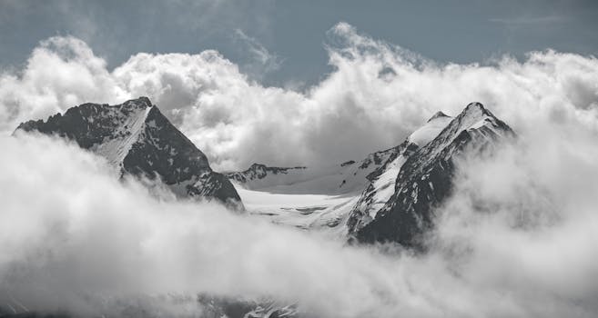 Captivating view of snow-capped mountain peaks shrouded in mist and clouds.
