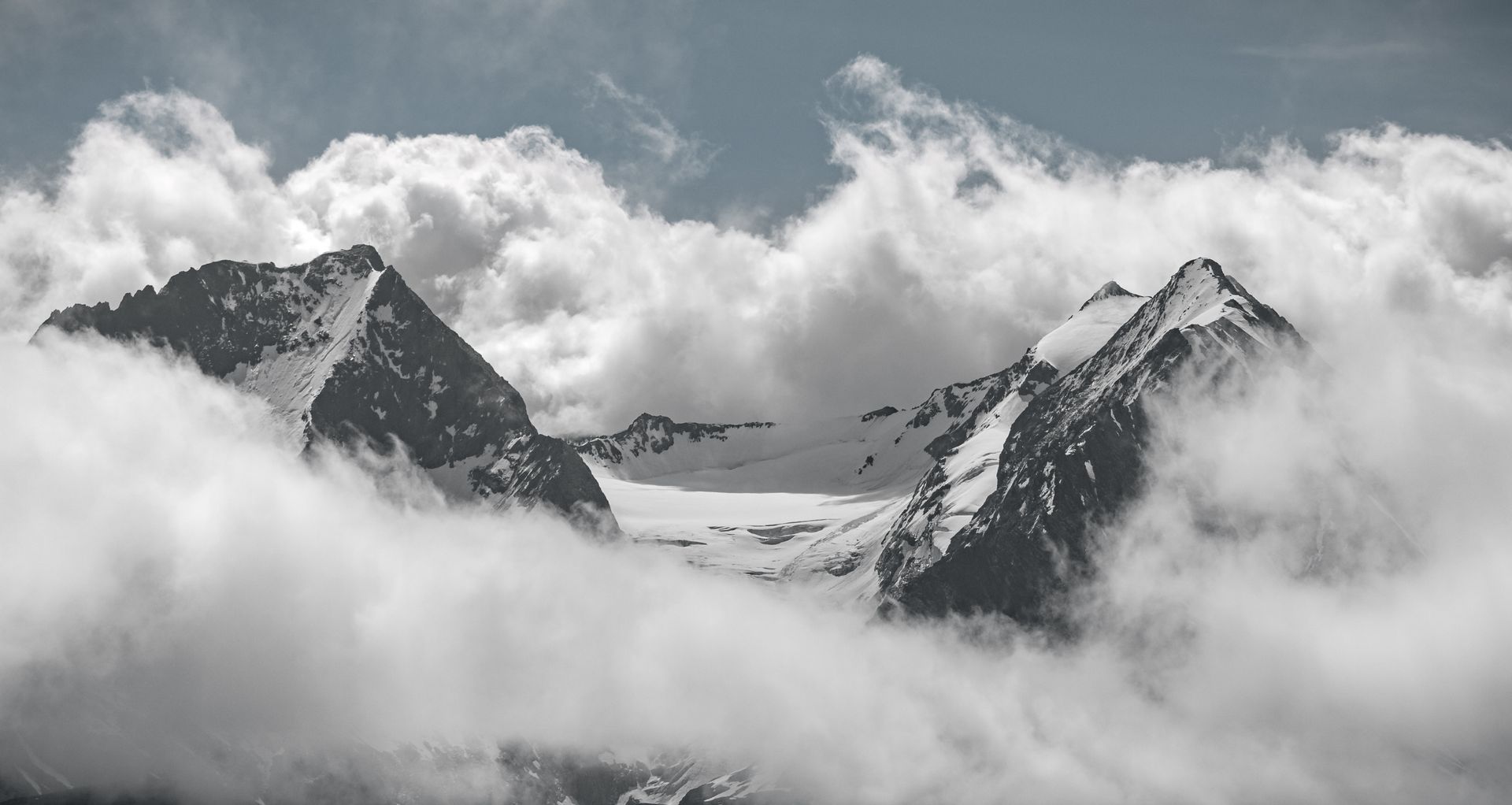 Captivating view of snow-capped mountain peaks shrouded in mist and clouds.