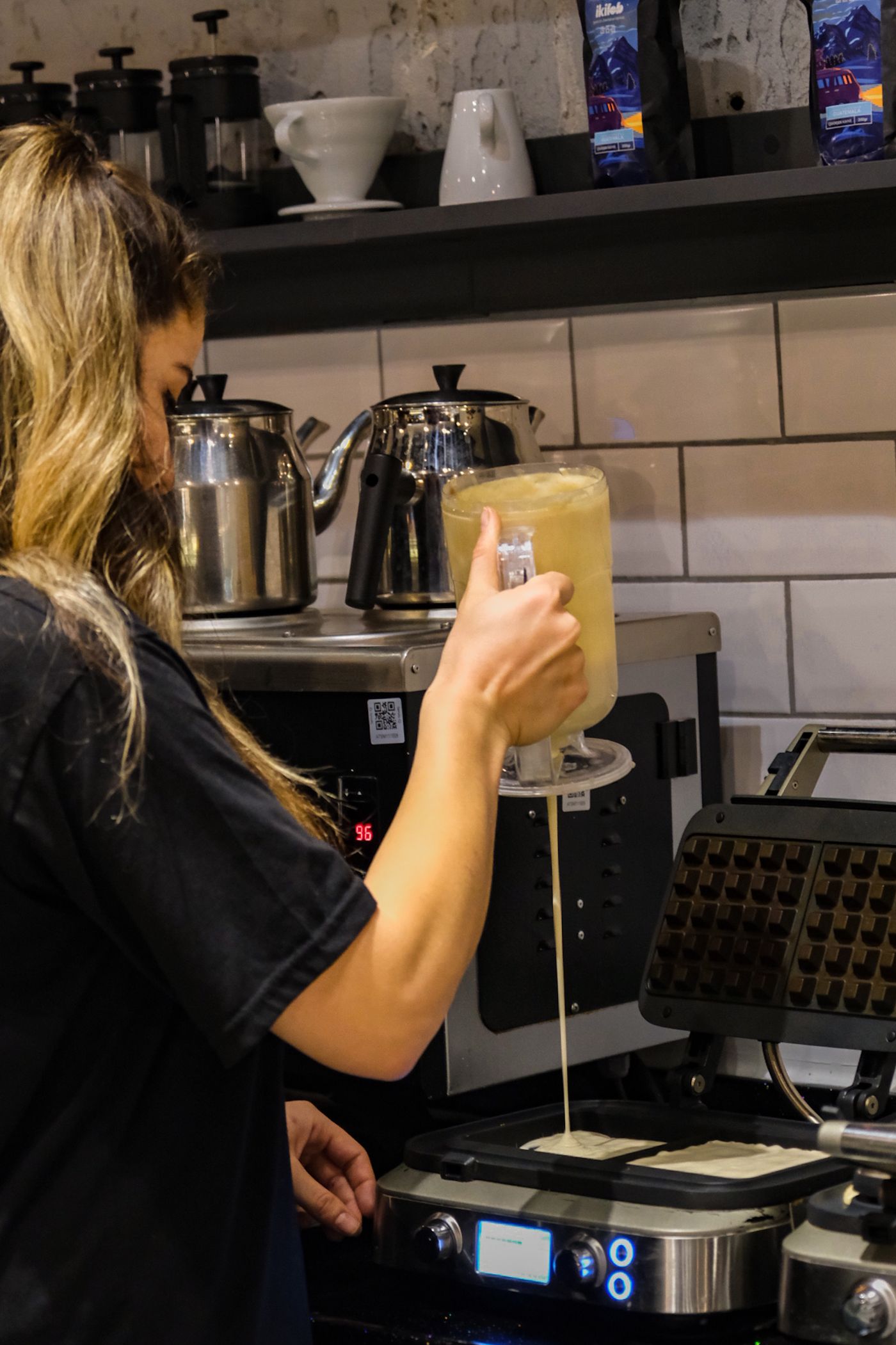 Waffle batter being poured into an open waffle maker