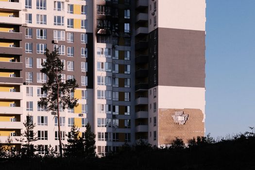 Exterior view of a modern apartment building in Ukraine showing visible damage to the structure.