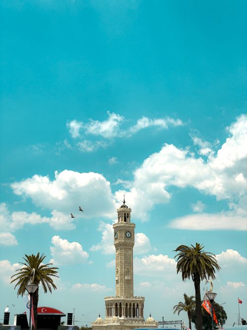 Free Capture of the famous İzmir Clock Tower with palm trees and vibrant blue sky. Stock Photo
