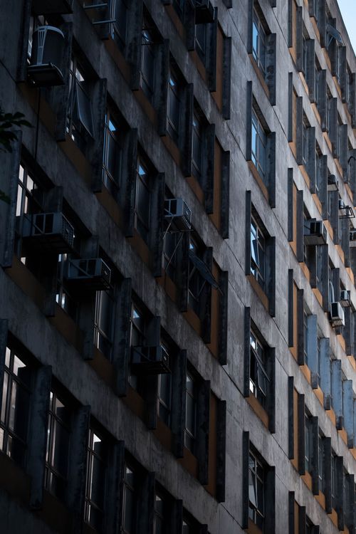 Free A modernist high-rise facade featuring numerous windows and weathered details in an urban setting. Stock Photo