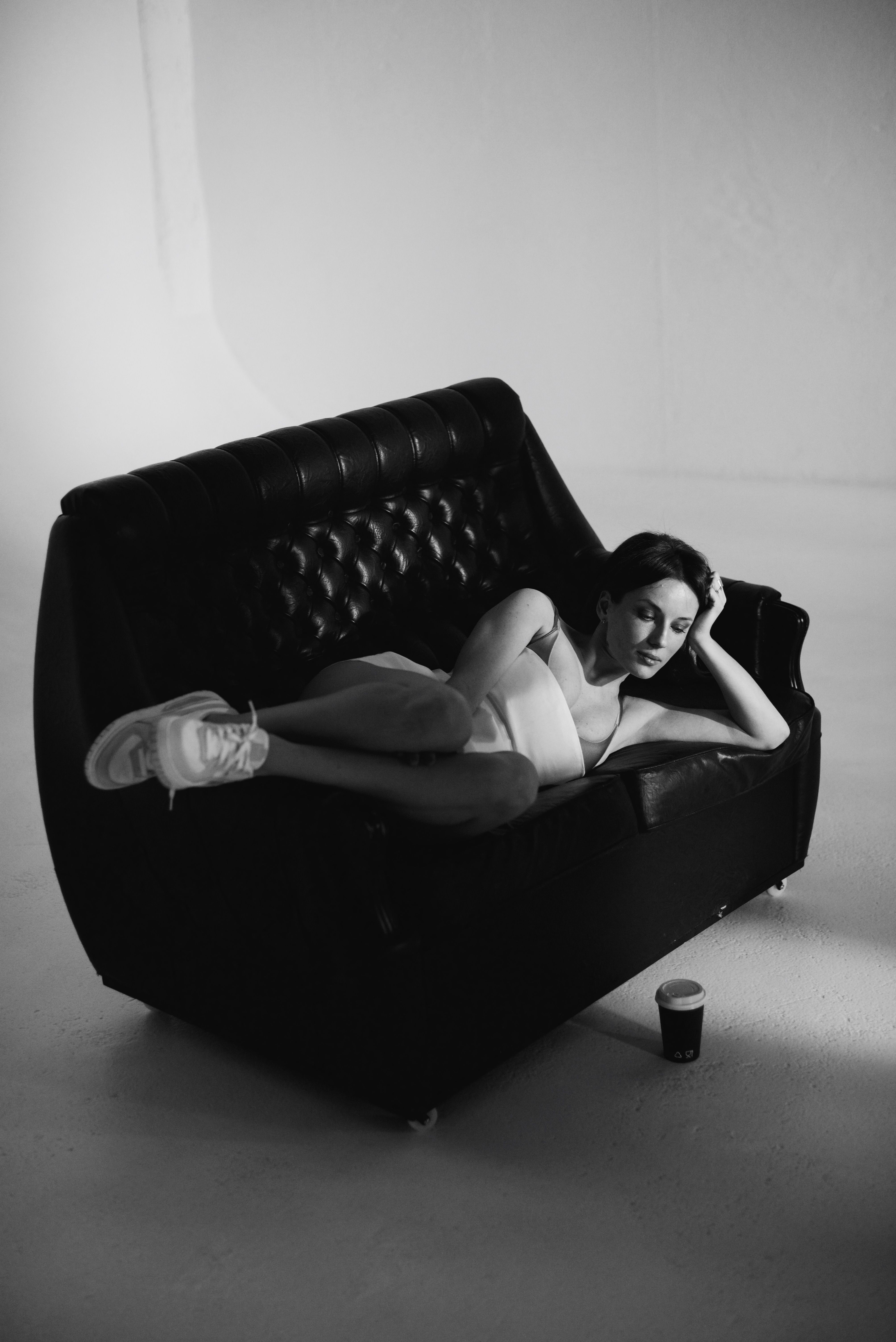 Monochrome image featuring a woman relaxing on a sofa with a coffee cup nearby, conveying a serene mood.