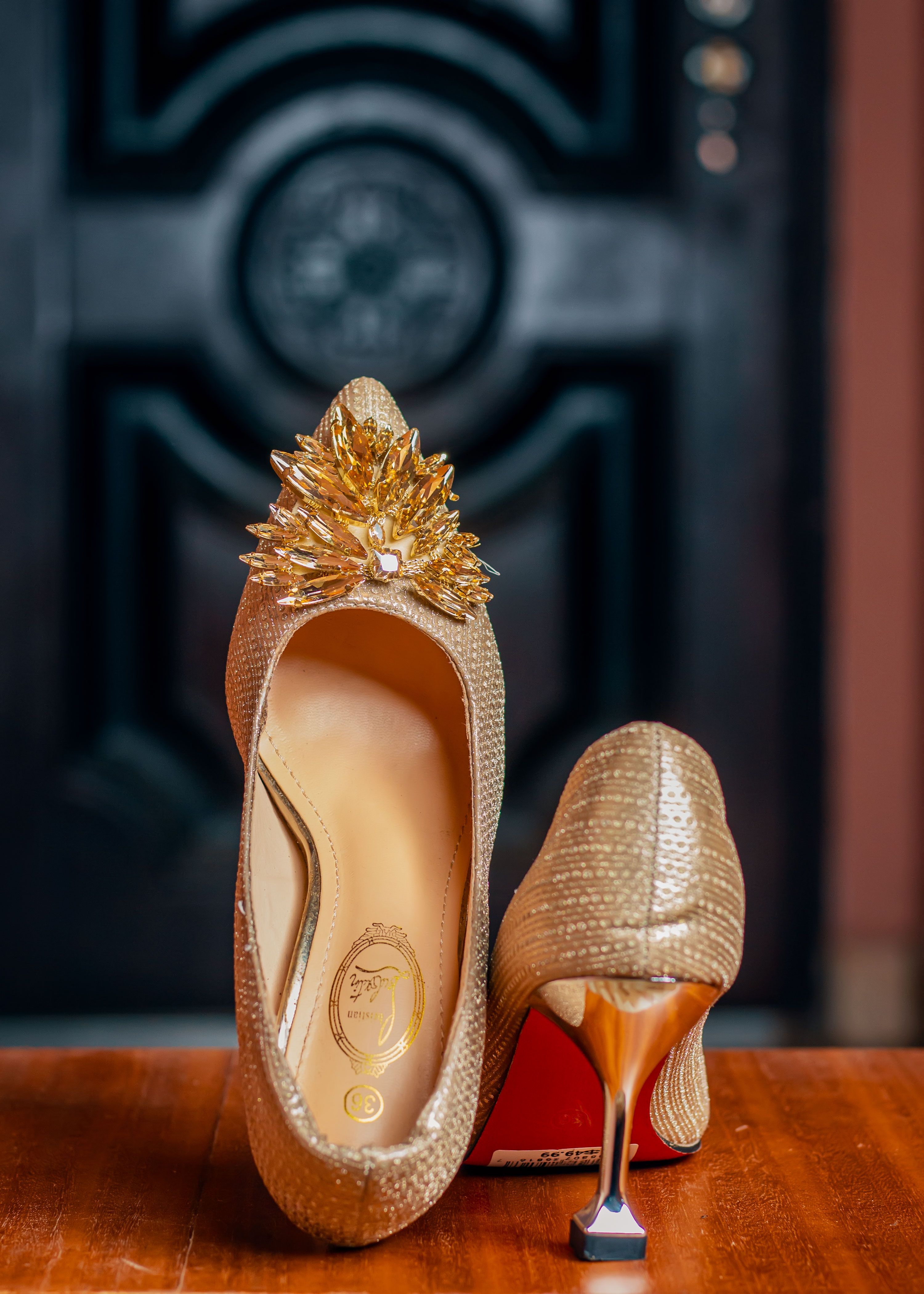 Close-up de sapatos de salto alto dourados com decoração em uma superfície de madeira.