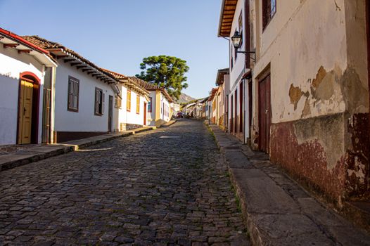Explore an idyllic cobblestone street lined with charming, historic buildings under a clear blue sky.