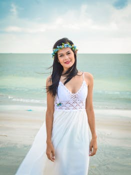 在巴西累西岛的海滩上，一位身穿白色连衣裙的亚洲女子正在微笑